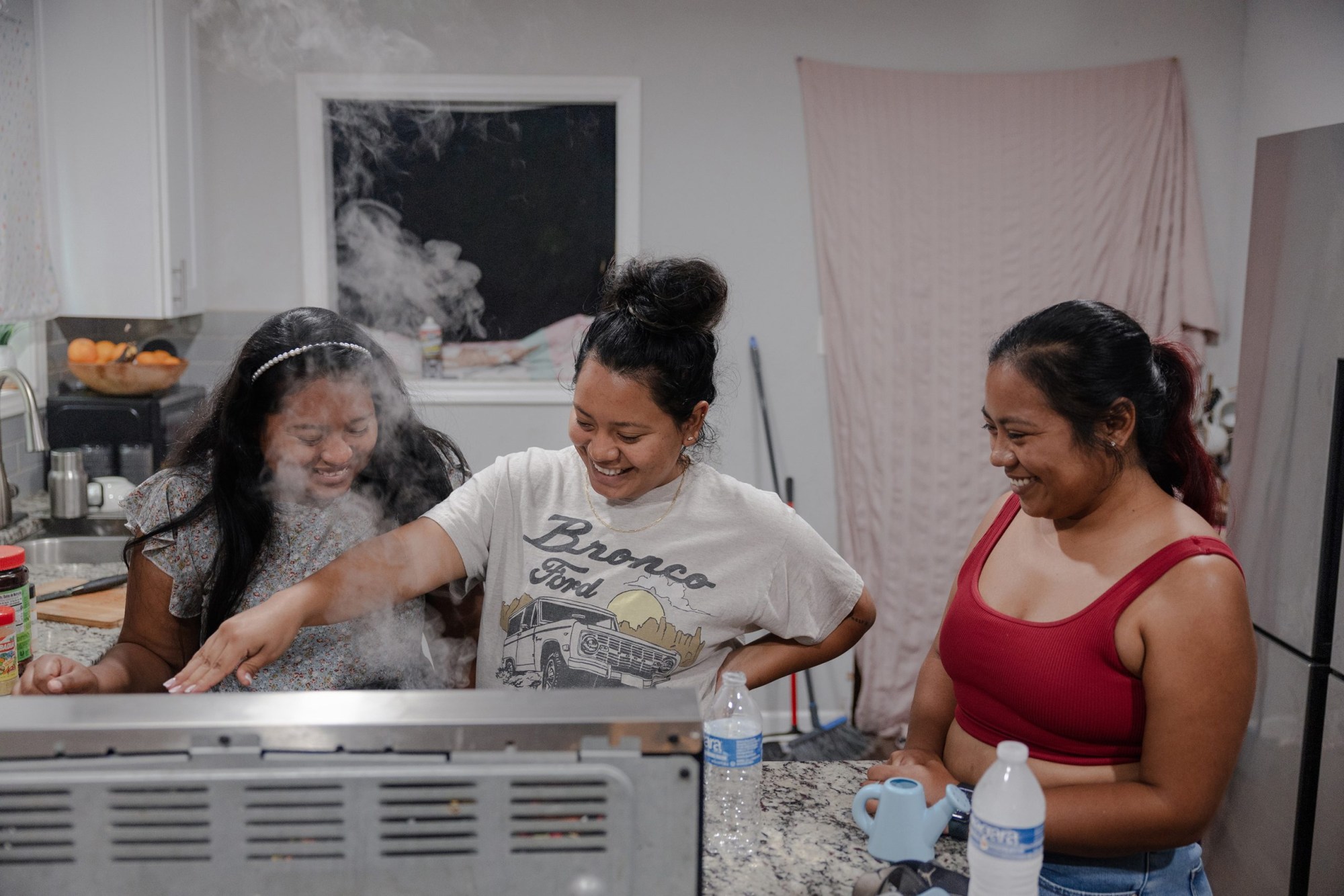 Sisters Ester, Abigail and Lisbet (left to right) talk as they cook at Abigail’s house in June. In the absence of Margarita, the sisters have looked out for their younger brothers.