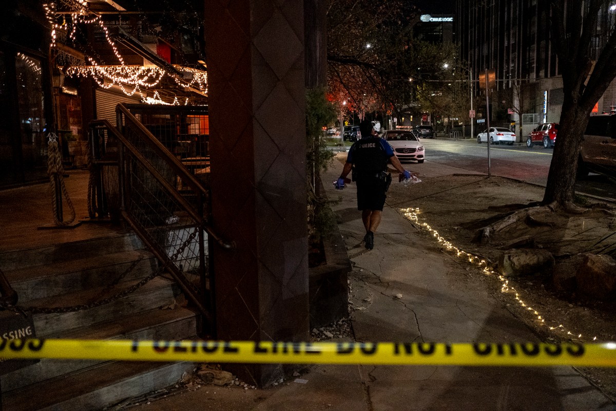 An Austin police officer cleans up crime scene remnants near the bar where a fatal shooting left three dead and at least 14 wounded, in downtown Austin on March 1, 2026.
