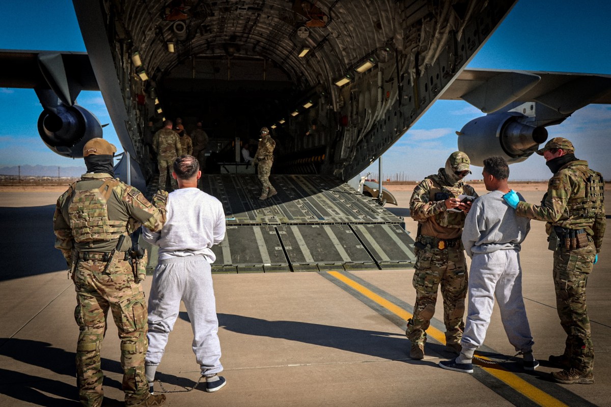 Two men in shackles are loaded onto a flight to Guantanamo Bay in a photo released by the Department of Homeland Security.