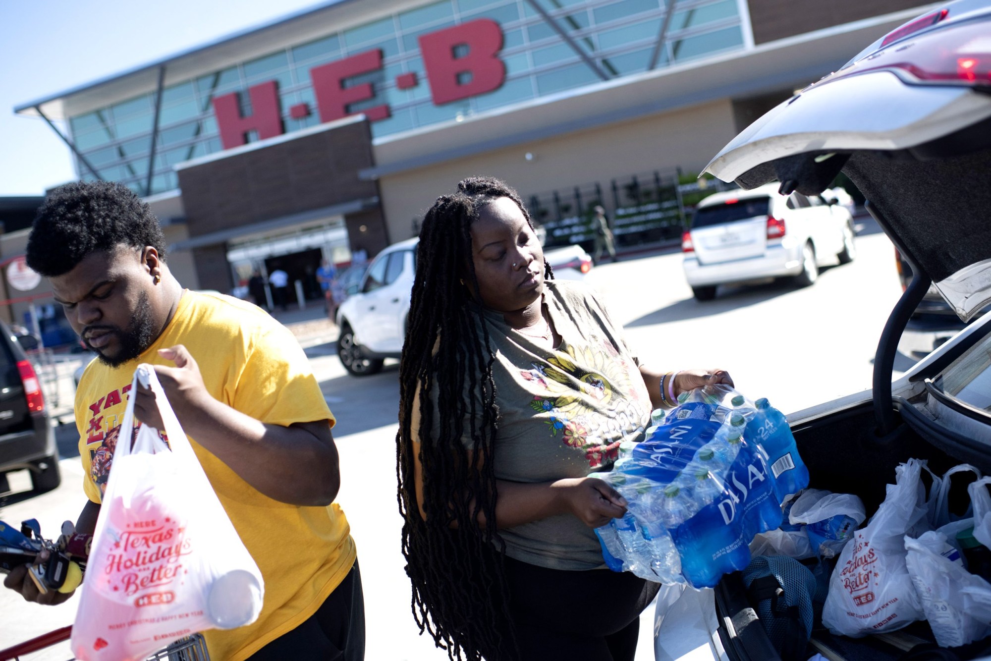 Eboni Davis and Jesse Holloway load water into their car outside an H-E-B grocery store in Houston on Nov. 28, 2022.