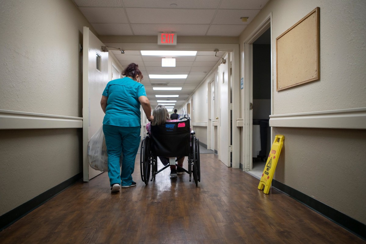 An employee of the Amistad Nursing and Rehabilitation Center walks with a resident on April 1, 2021.